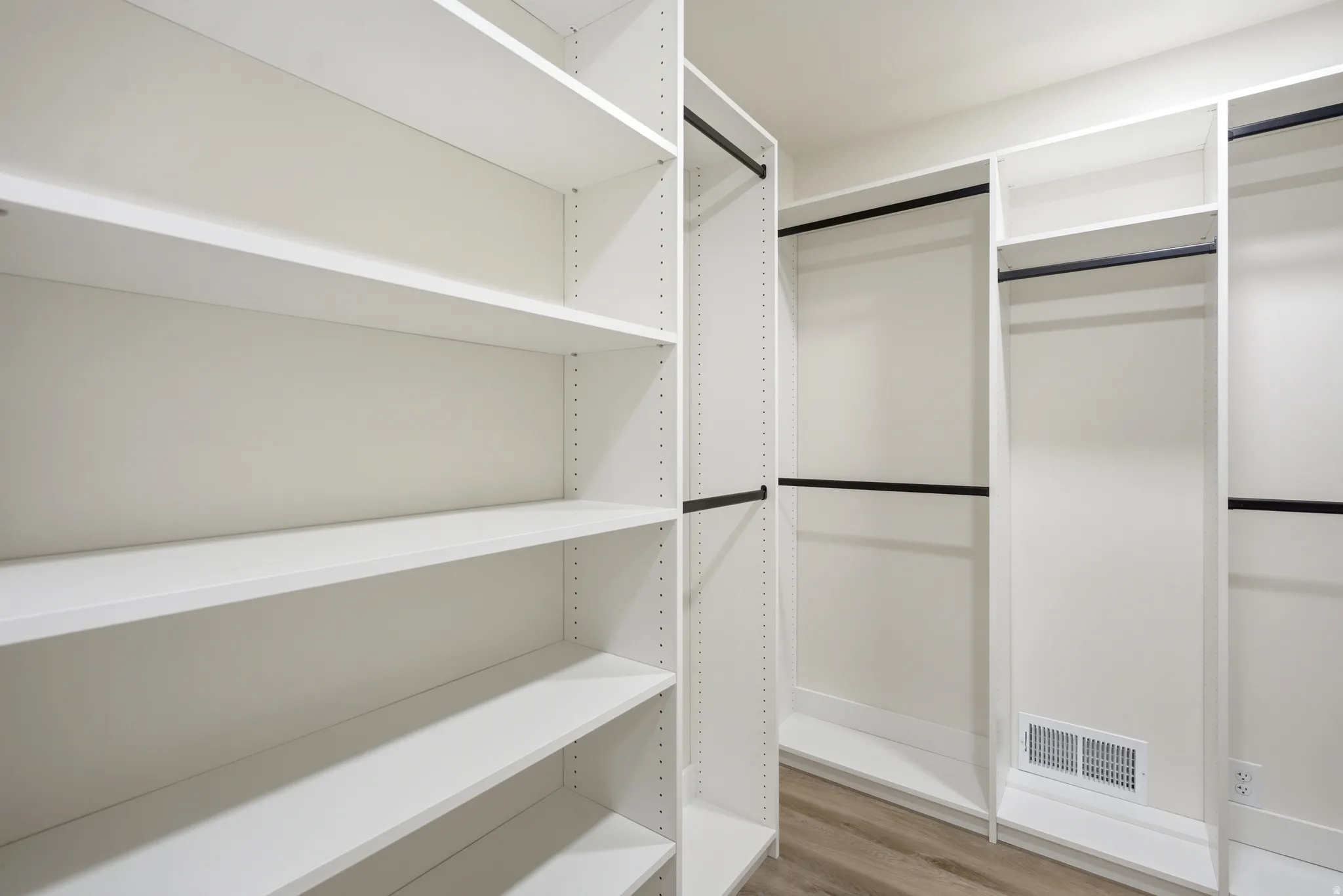 Custom closet system featuring white shelving and black hanging rods