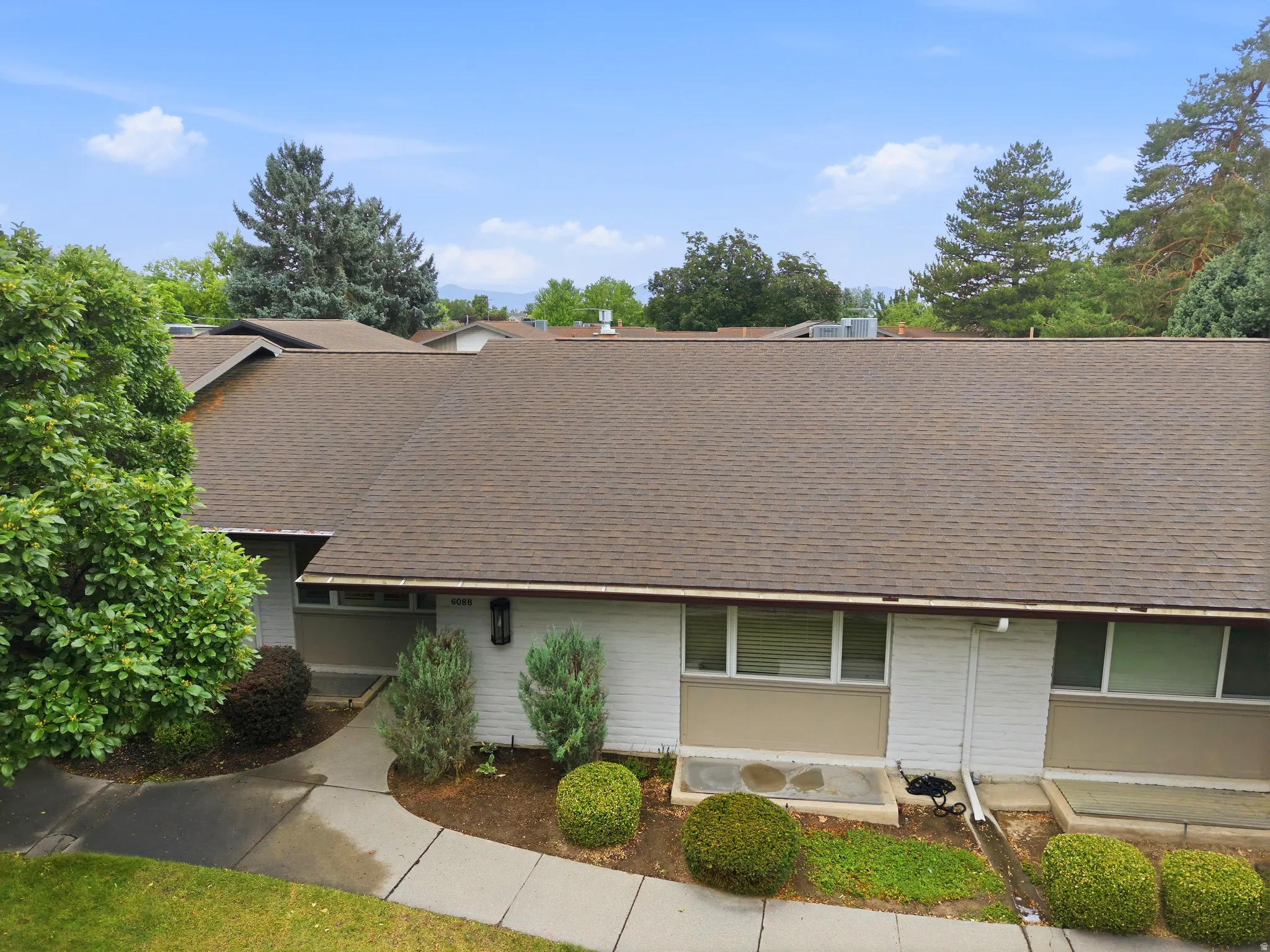 Brown shingle roof with a light-colored exterior and multiple windows