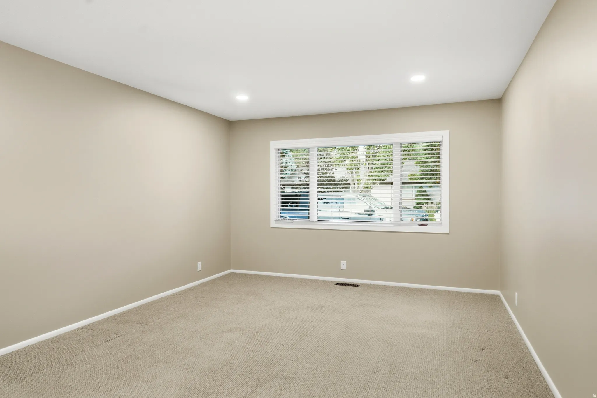 Neutral wall tones, recessed lighting, white baseboards, and light-colored carpeting