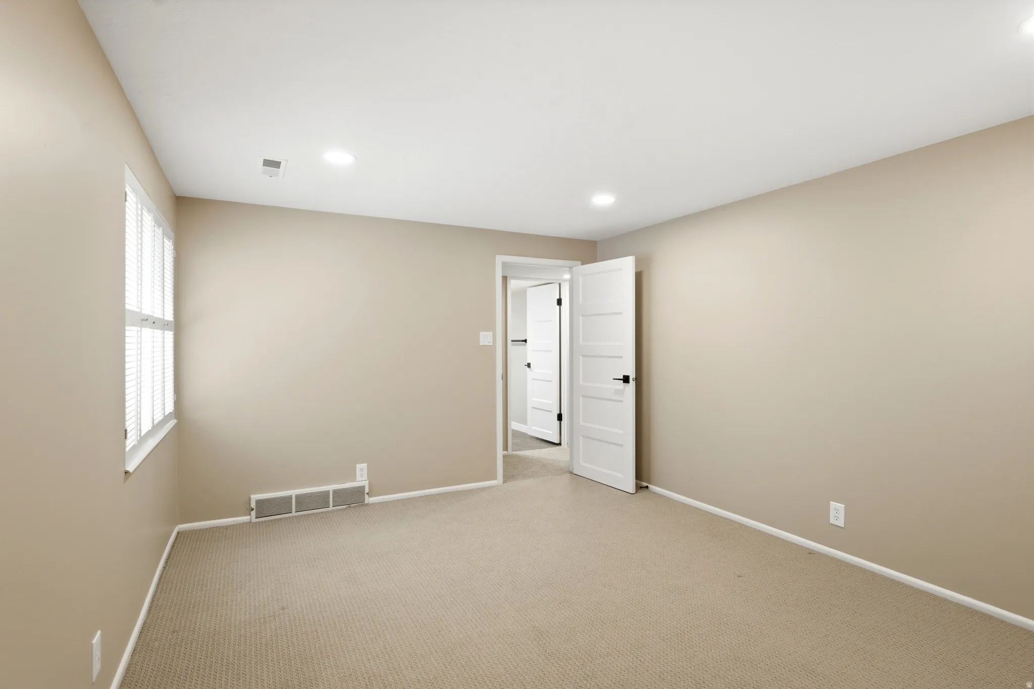 Neutral-toned room featuring light beige walls and a light brown carpet
