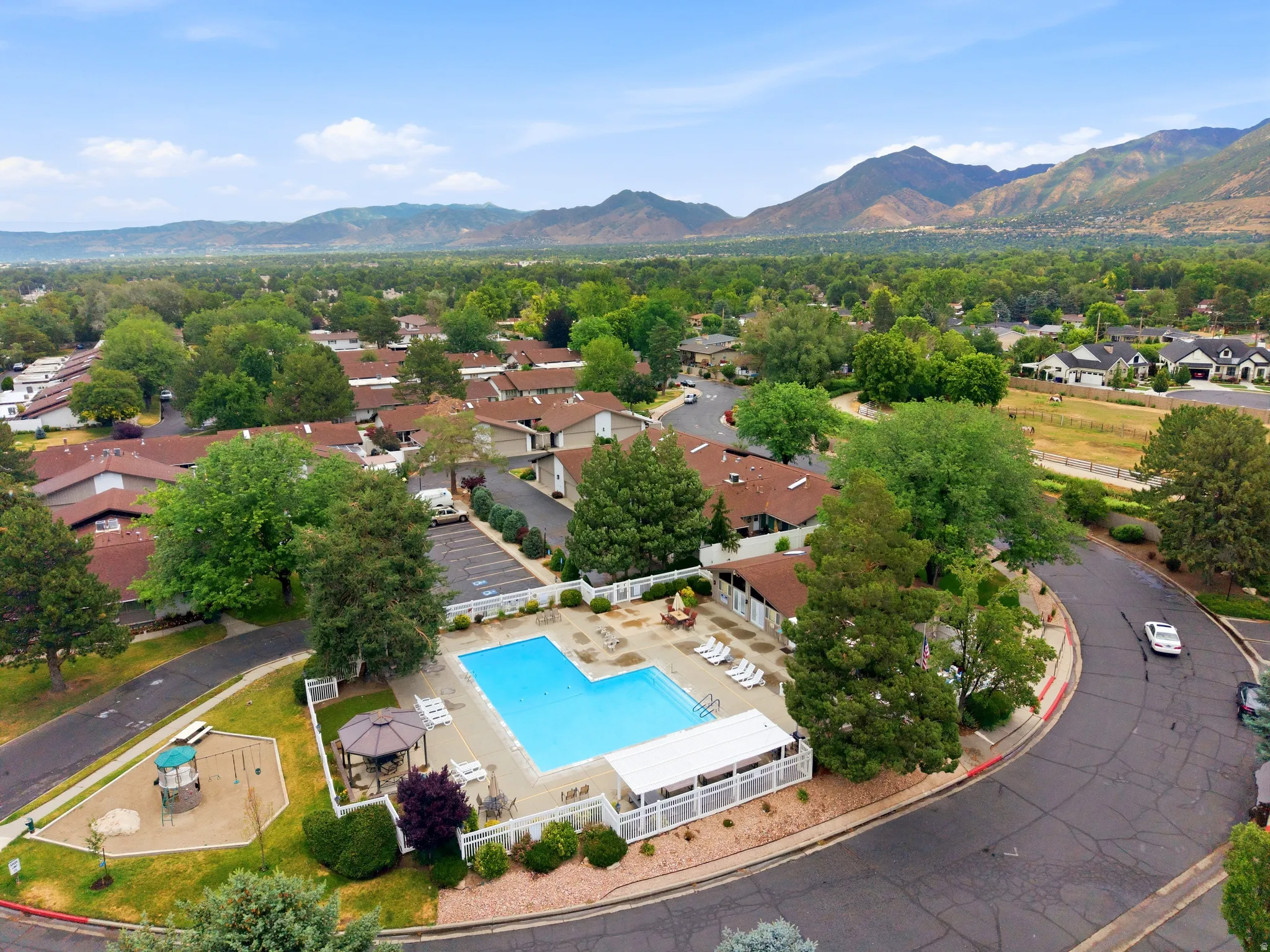 Community swimming pool with surrounding patio, covered lounge area, and adjacent gazebo