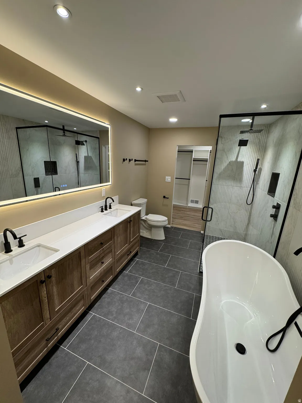 Spacious bathroom featuring a freestanding tub, expansive walk-in shower with dual shower heads, and a double vanity with ample storage