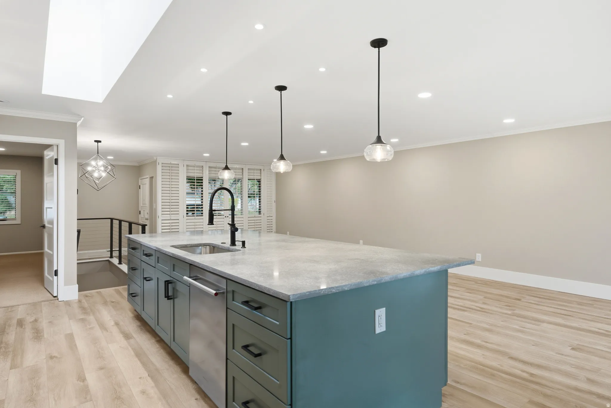 Spacious kitchen island with a built-in sink and dishwasher, featuring a light-colored countertop and green base cabinetry with dark hardware