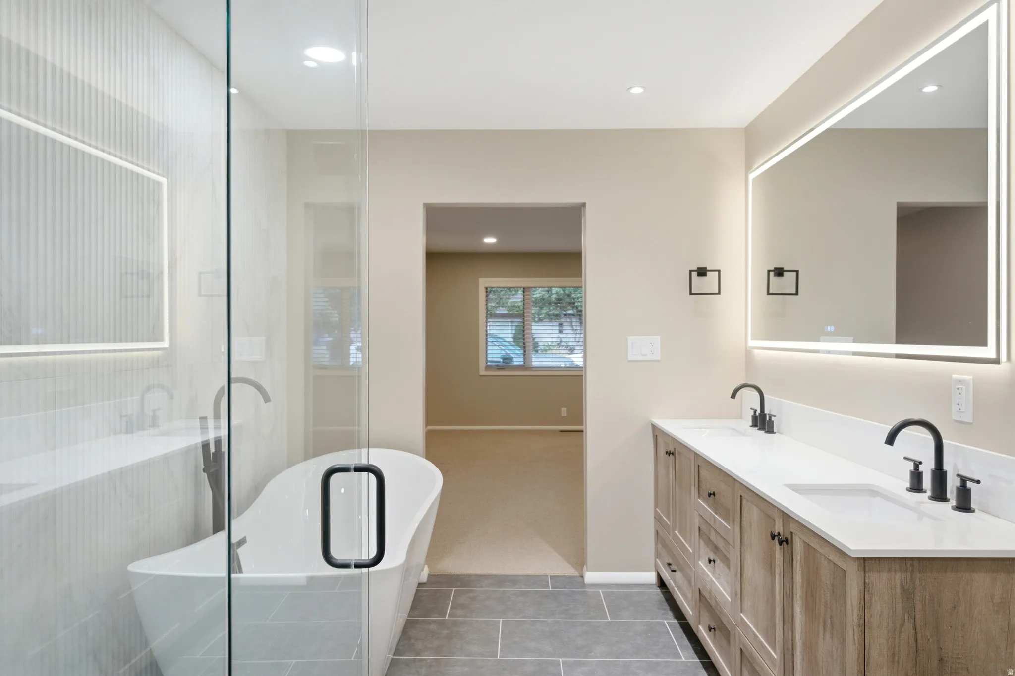 Freestanding soaking tub alongside a frameless glass shower enclosure