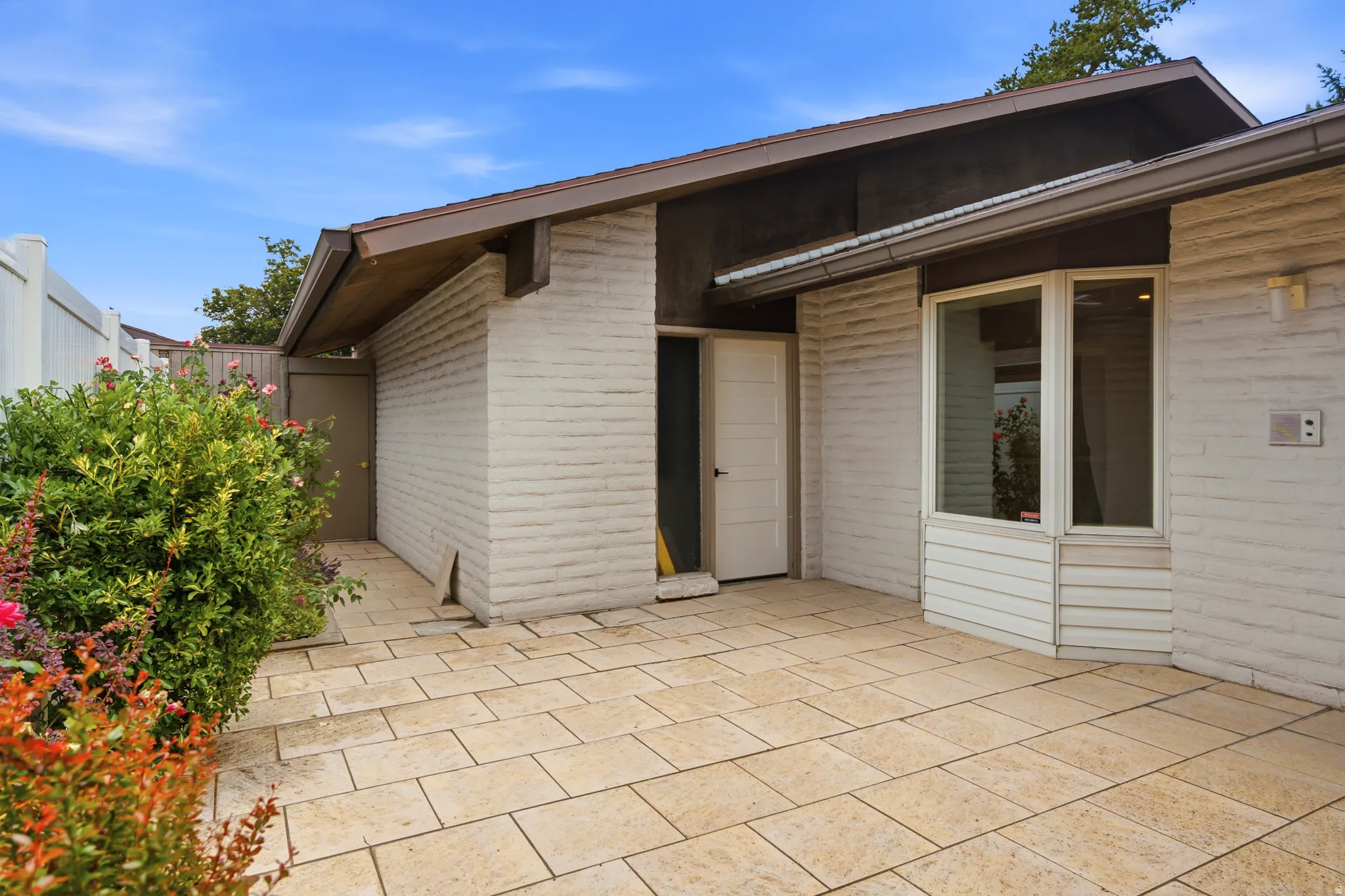 Outdoor patio featuring large format pavers and white brick exterior