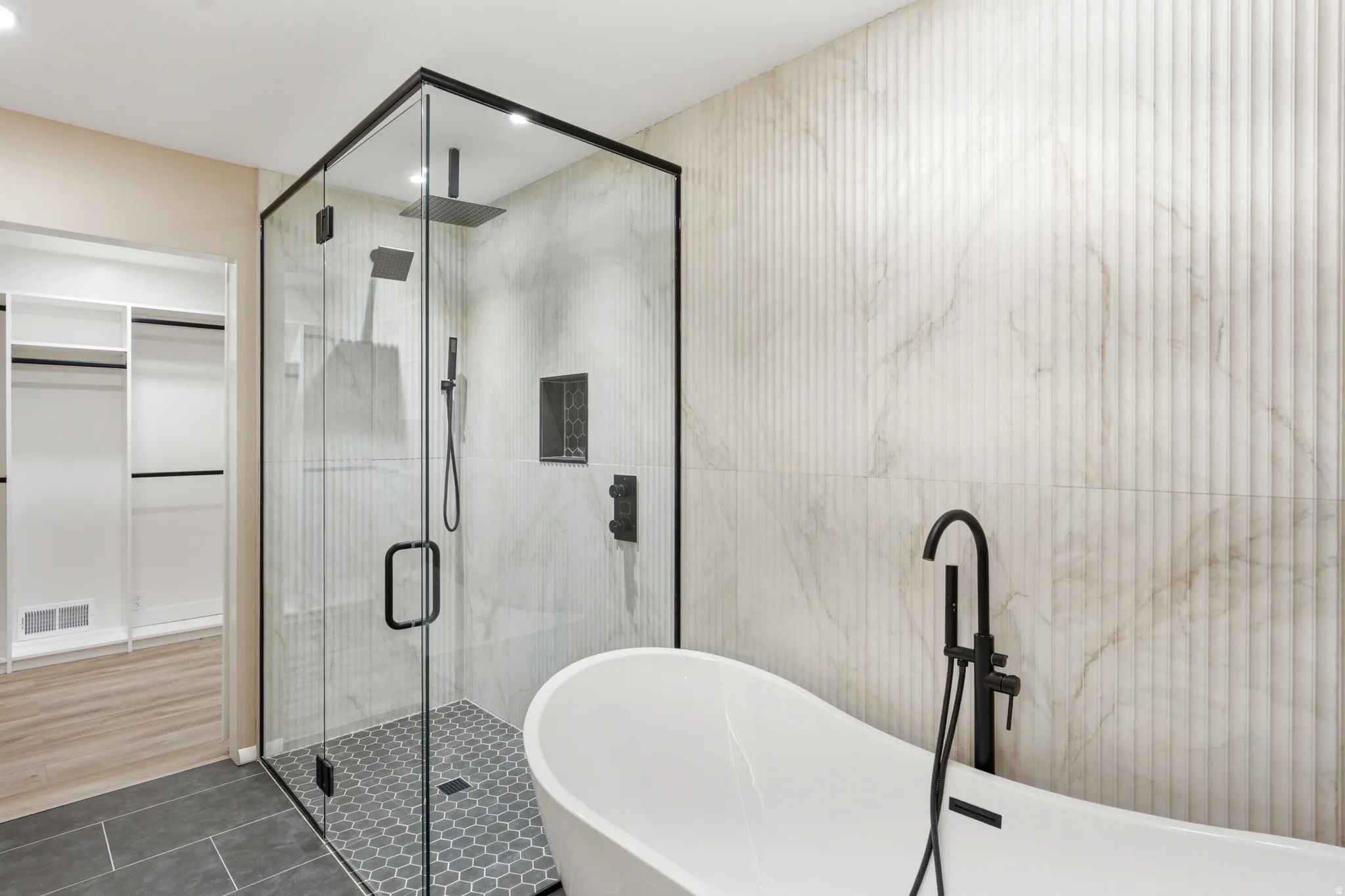 Modern bathroom featuring a freestanding tub with a matte black floor-mounted faucet, a frameless glass shower enclosure with matte black hardware, and a rainfall showerhead