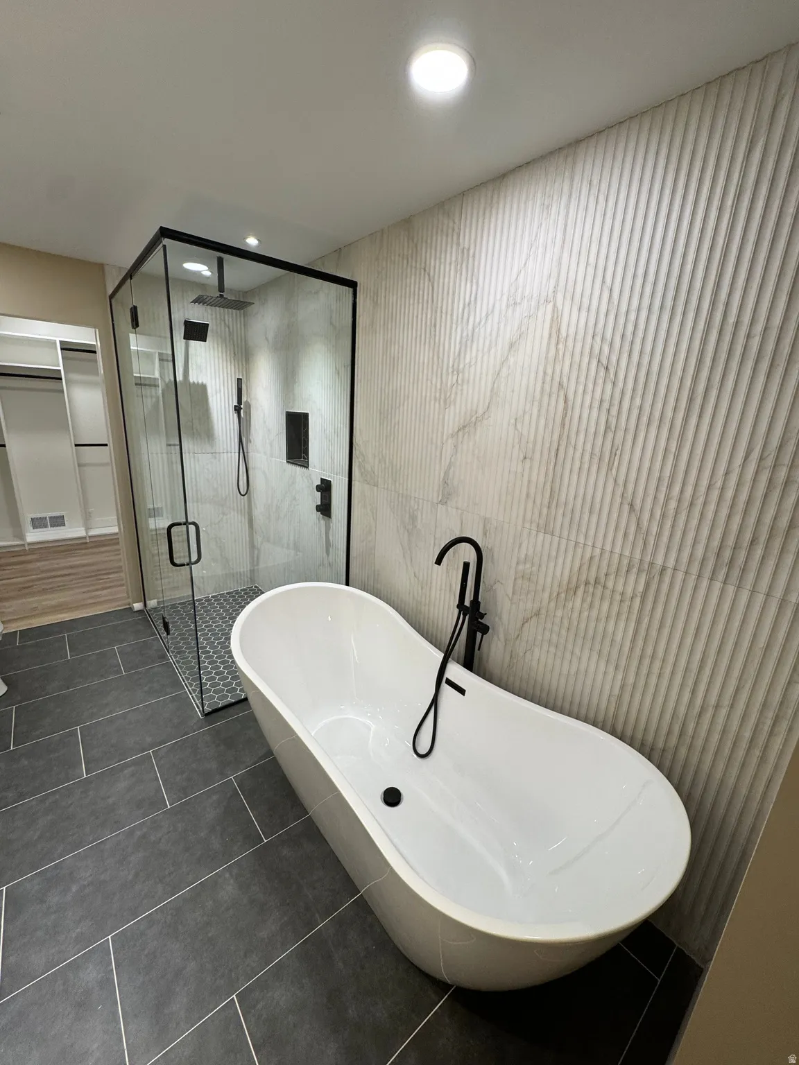 Freestanding soaking tub with matte black floor-mounted faucet