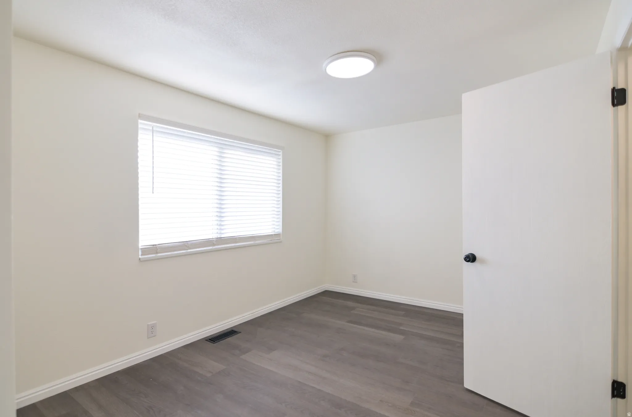 Room featuring wood-finish flooring, white baseboards, and neutral wall tones