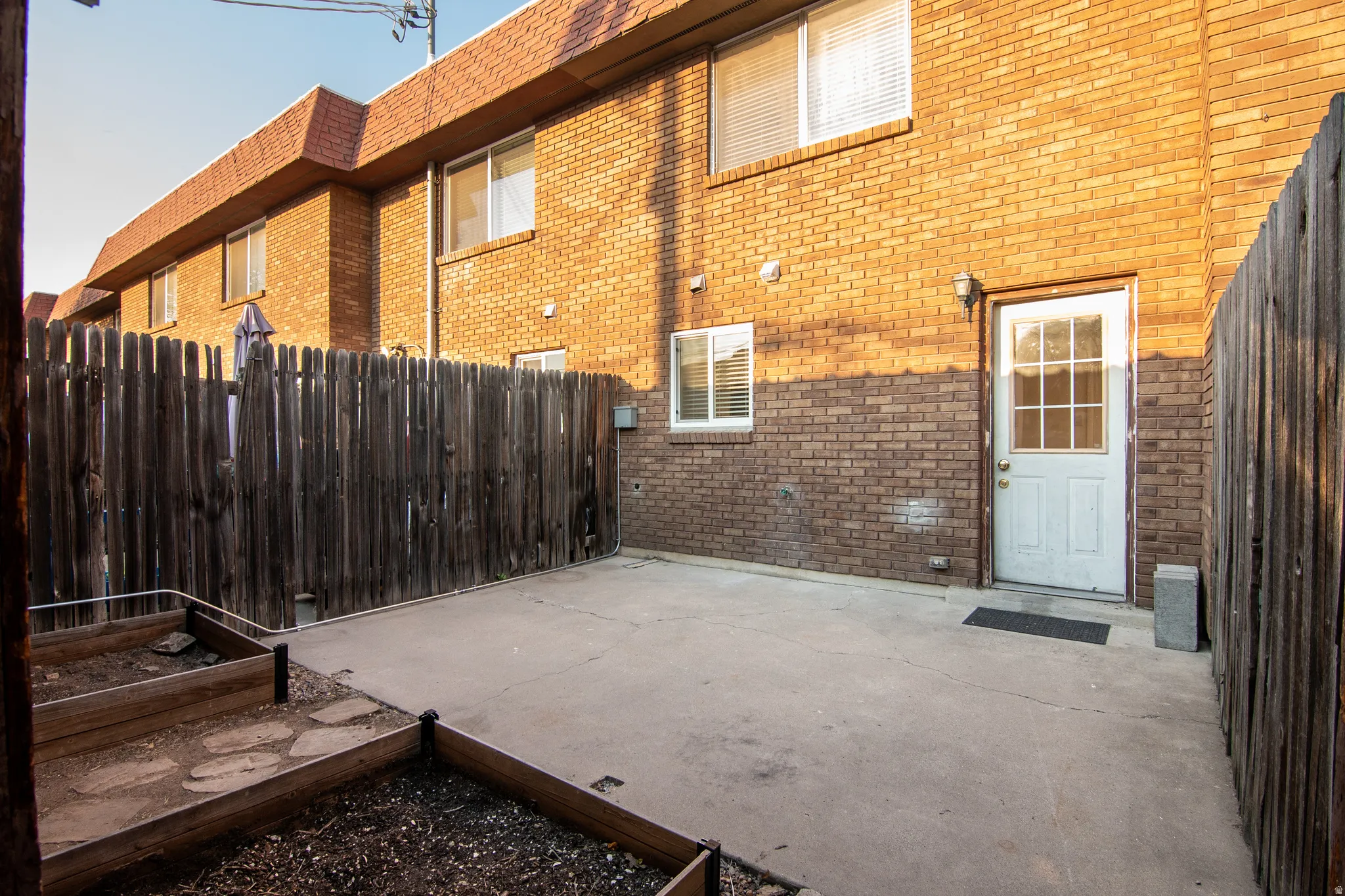 Private patio area featuring concrete paving, wood fencing, and raised garden beds