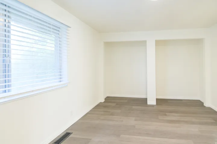 Room featuring wood-finish flooring, recessed lighting, and a window with horizontal blinds