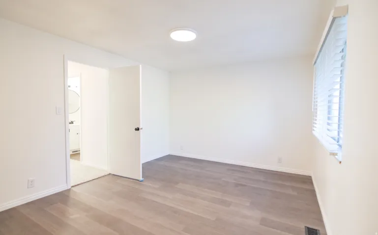 Room with wood-finish flooring, white walls, and a recessed ceiling light fixture