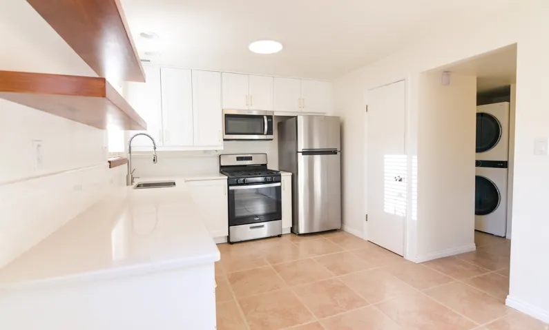 Modern kitchen featuring white cabinetry, light-toned countertops, stainless steel appliances, and a tiled floor