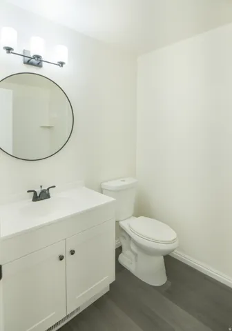 Bathroom featuring a white vanity with integrated sink, black-finish faucet, circular mirror, and three-light fixture