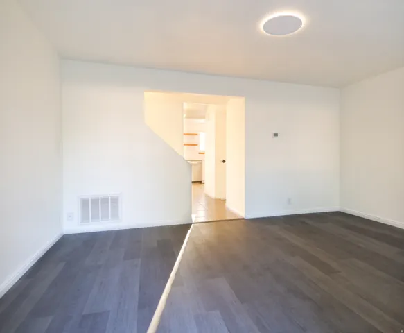Spacious room featuring wood-finish flooring, white baseboards, and neutral wall paint