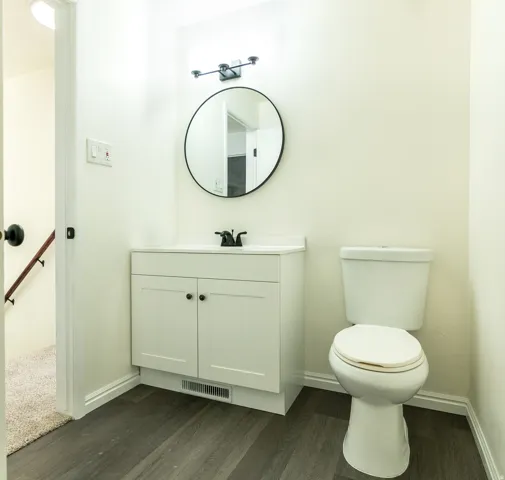 Bathroom featuring a white vanity with cabinet storage, a circular mirror, and a modern black light fixture