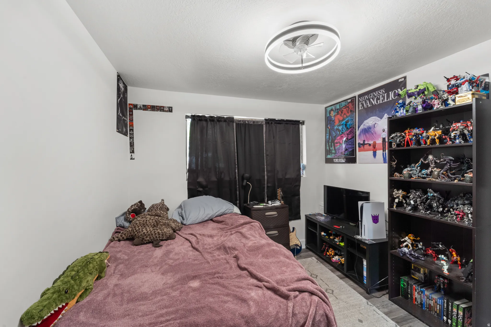 Bedroom featuring a ceiling fan with integrated lighting, window with dark drapes, and light-colored walls