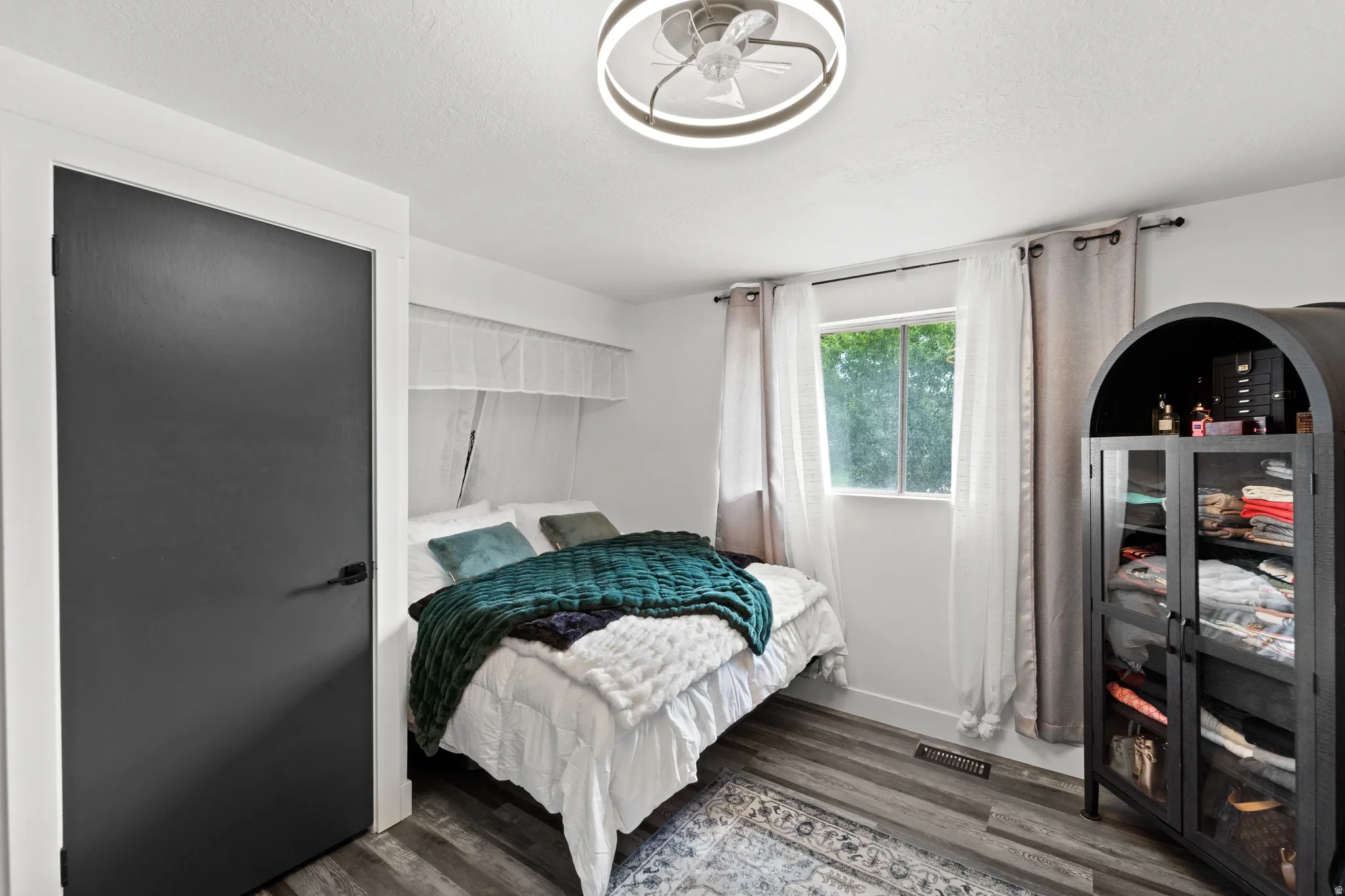 Bedroom featuring wood-finish flooring, a contemporary ceiling fan, and a window with natural light