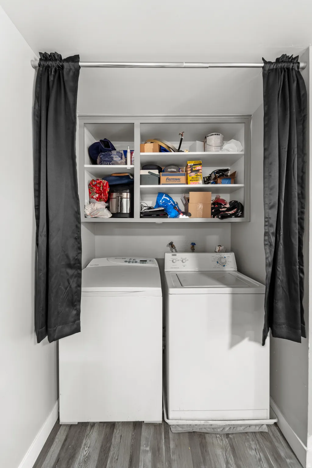 Dedicated laundry area featuring wood-finish flooring and an upper storage cabinet