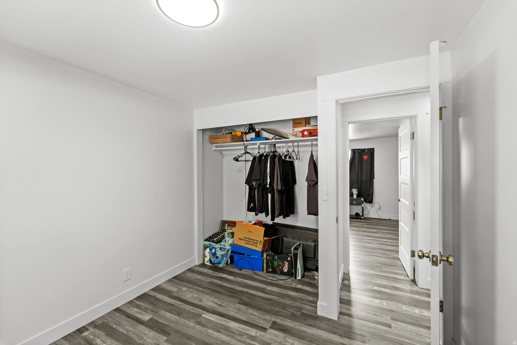 Interior room featuring wood-finish flooring and a built-in closet with shelving and a hanging rod