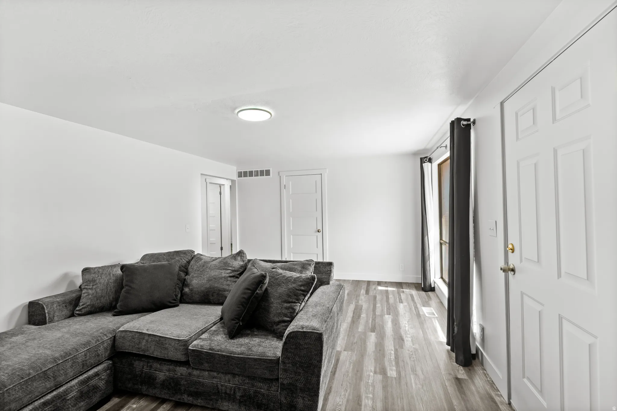 Spacious room featuring wood-finish flooring, white walls, and a recessed ceiling light