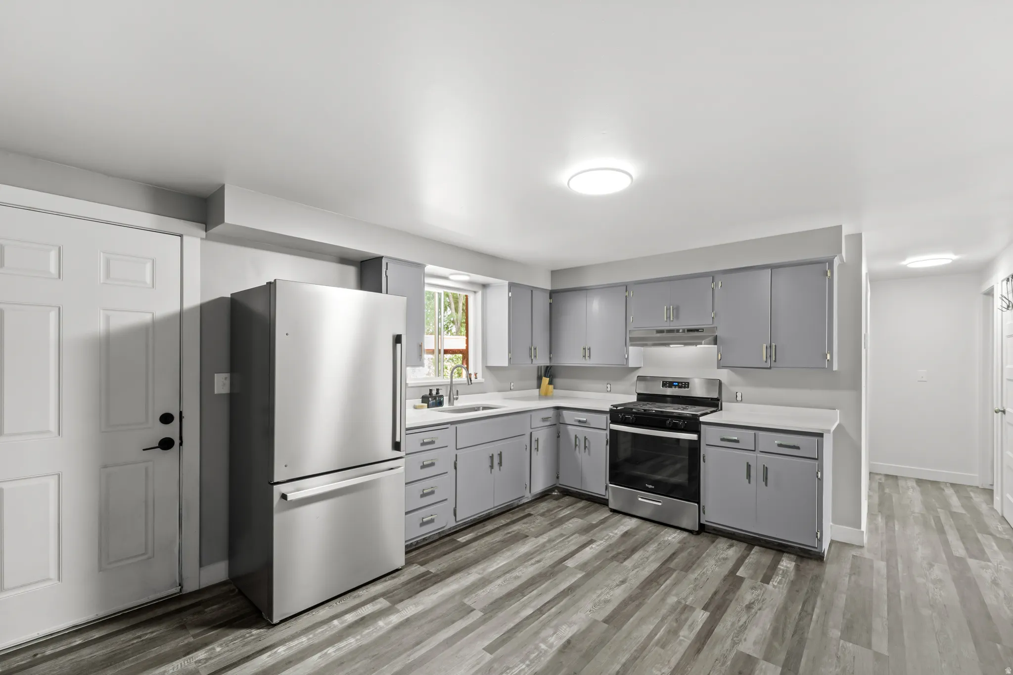 Kitchen featuring stainless steel appliances, gray cabinetry, white countertops, and wood-finish flooring