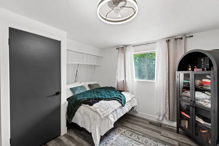 Bedroom featuring wood-finish flooring, a contemporary ceiling fan, and a window with natural light
