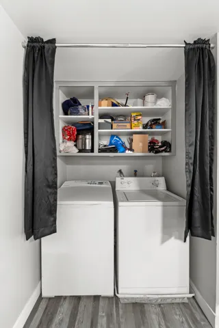 Dedicated laundry area featuring wood-finish flooring and an upper storage cabinet