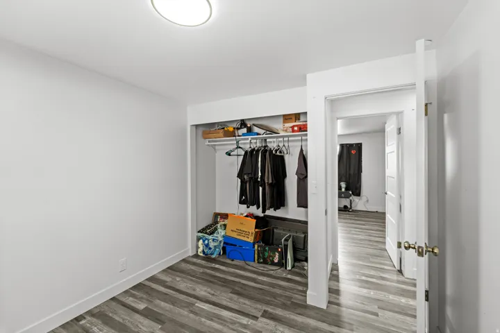 Interior room featuring wood-finish flooring and a built-in closet with shelving and a hanging rod