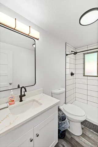 Modern bathroom featuring a white vanity with a quartz-look countertop, integrated sink, and matte black faucet