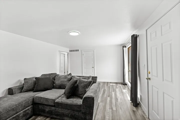 Spacious room featuring wood-finish flooring, white walls, and a recessed ceiling light