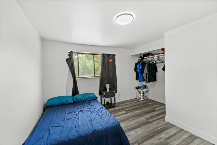 Interior room with light gray walls, wood-finish flooring, and a window with black privacy curtains