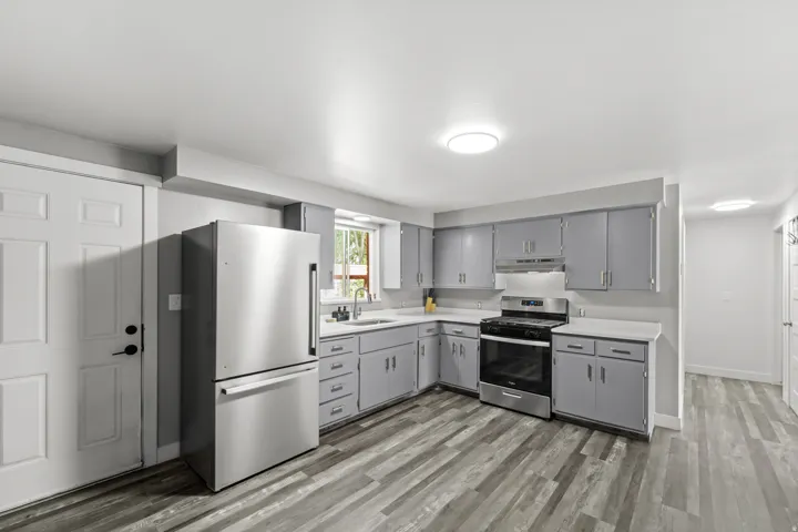 Kitchen featuring stainless steel appliances, gray cabinetry, white countertops, and wood-finish flooring