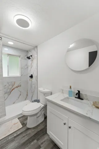 Bathroom featuring a walk-in shower with marble-look tile surround and matte black fixtures