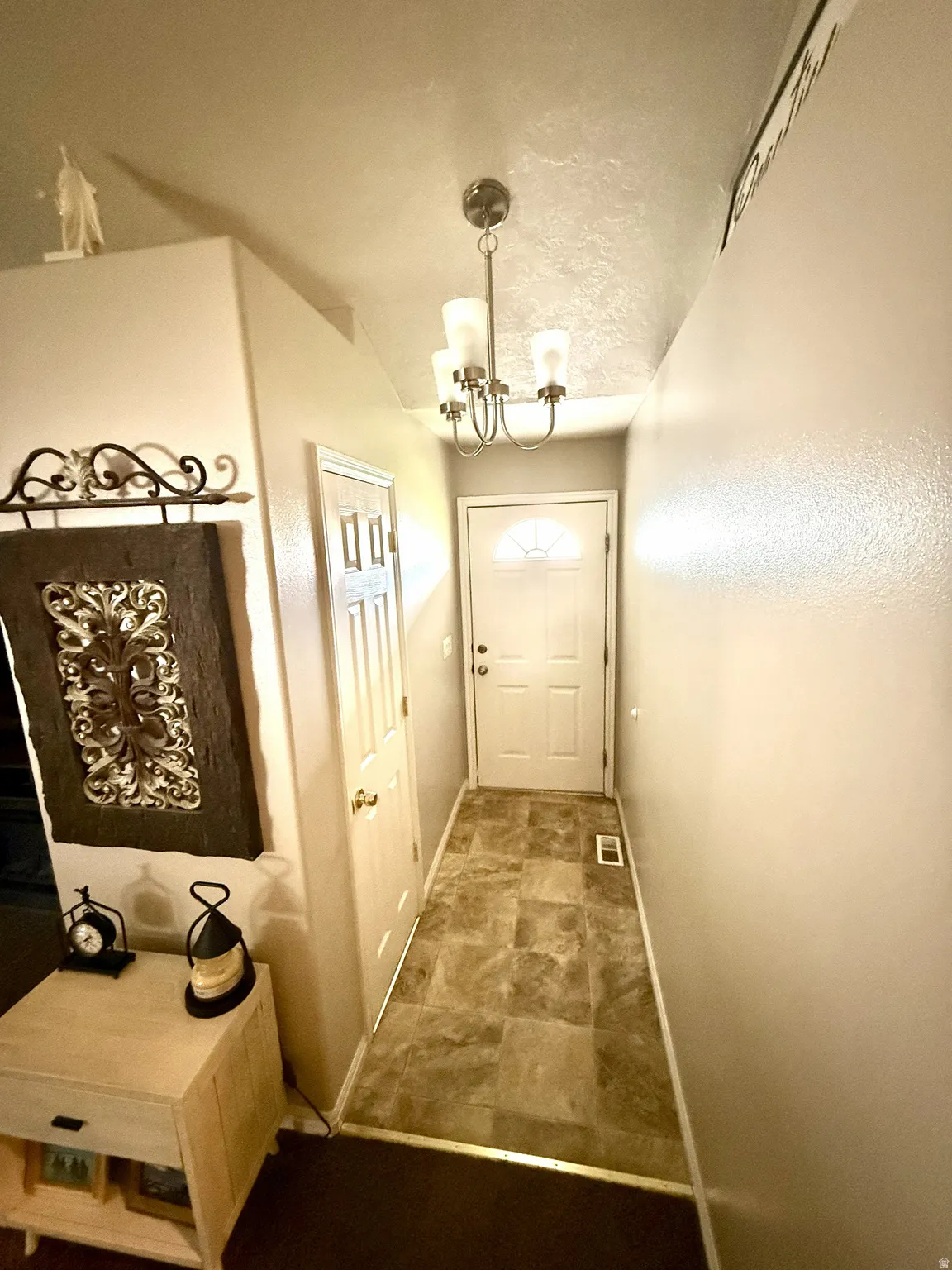 Entryway featuring tile-finish flooring, a contemporary chandelier, and a paneled entry door with an arched transom
