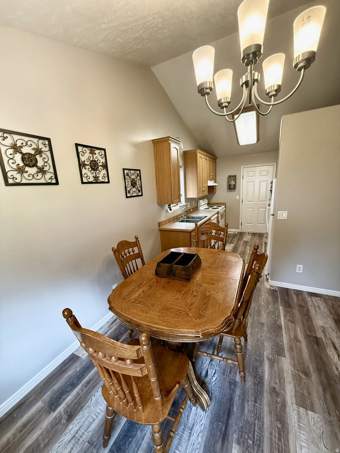 Dining area featuring wood-finish flooring, vaulted ceiling, and an updated multi-light chandelier