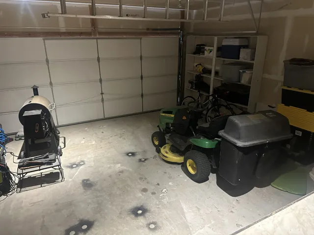 Attached garage featuring a sectional overhead door, concrete flooring, and built-in shelving