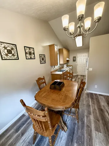 Dining area featuring wood-finish flooring, vaulted ceiling, and an updated multi-light chandelier