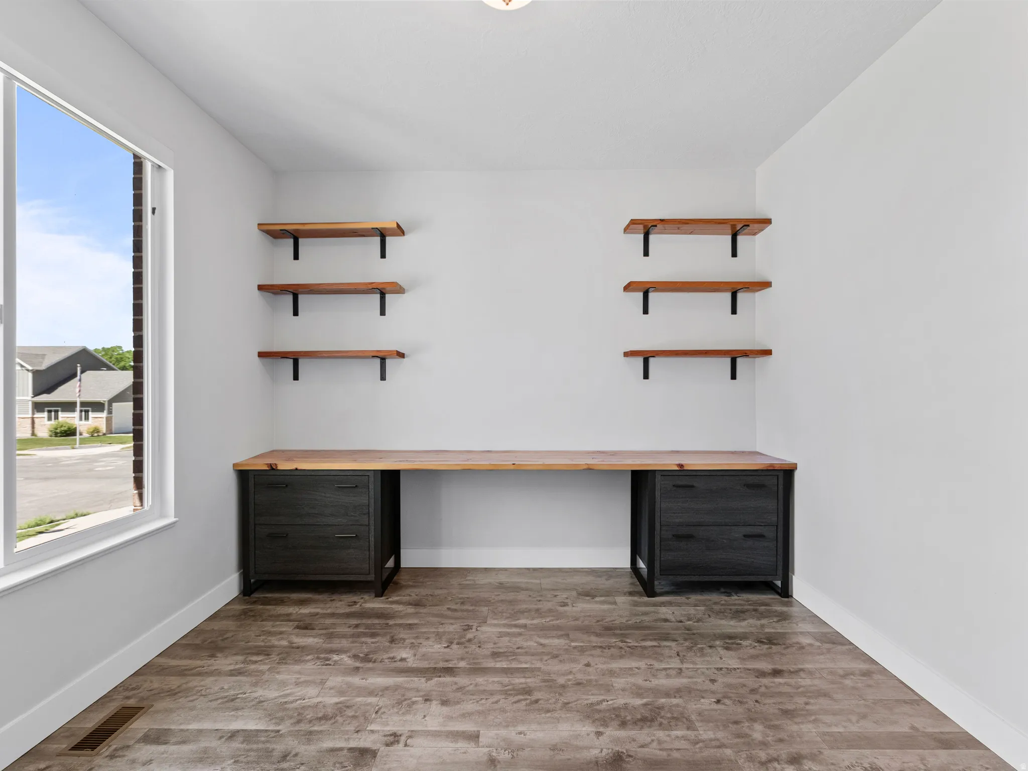 Dedicated space featuring a built-in wood-finish desk with dark cabinetry