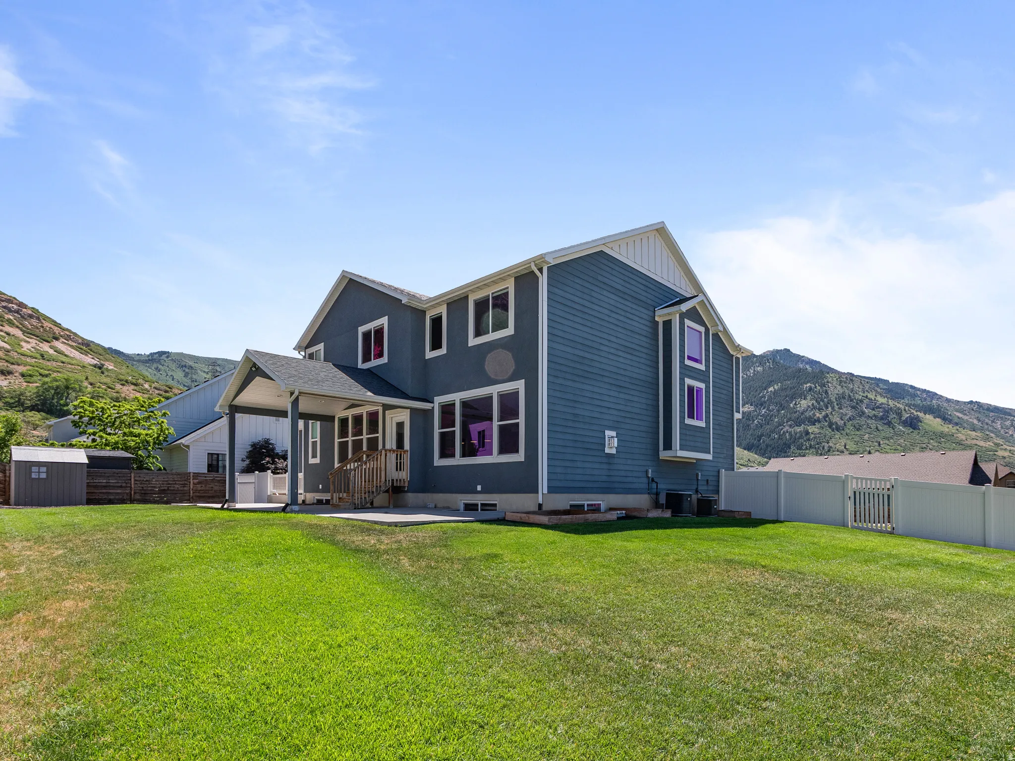 Expansive green lawn with a two-story residence featuring blue siding and white trim