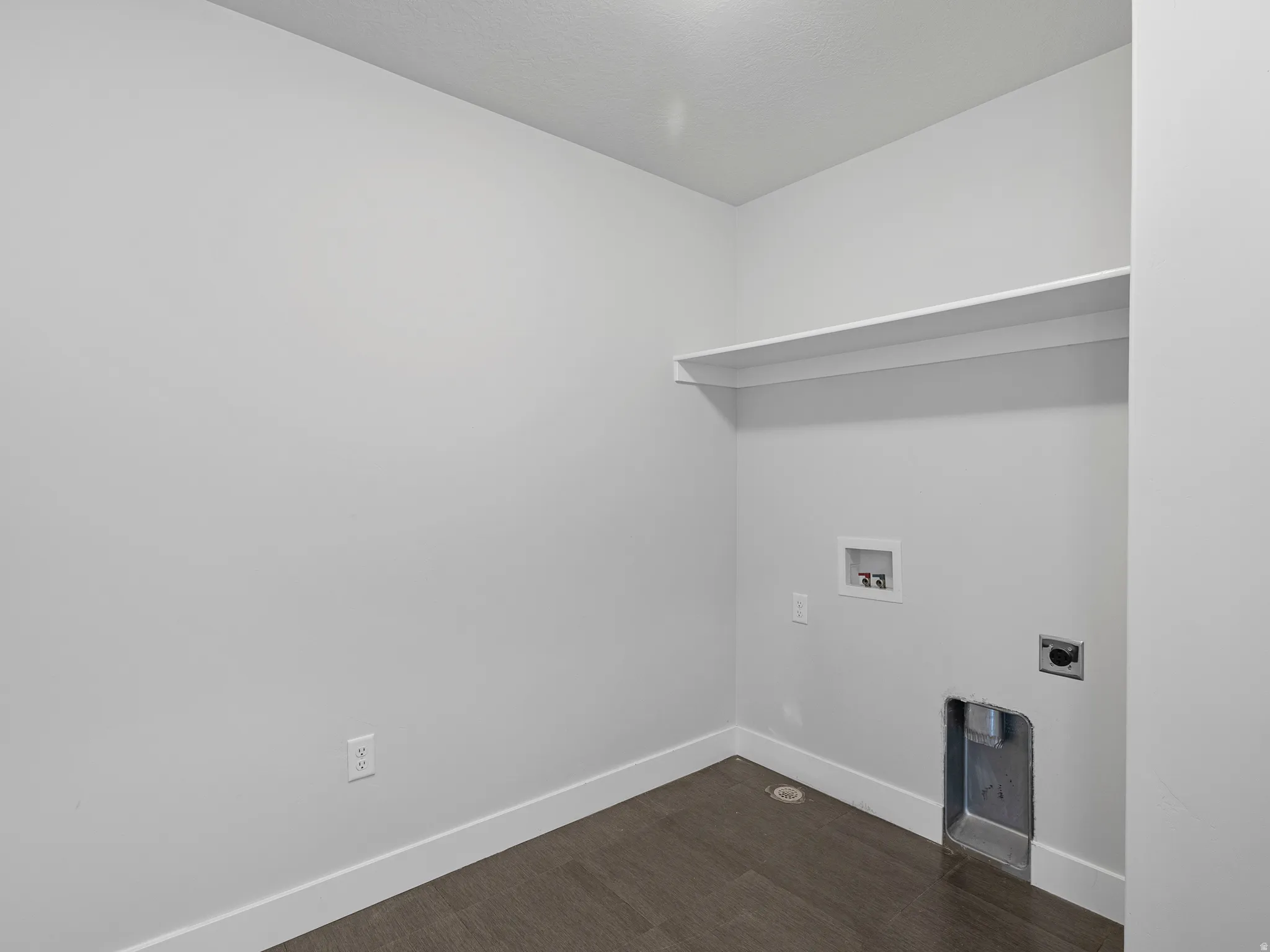 Dedicated utility space featuring a built-in shelf, wood-finish flooring, white baseboards, and essential hookups