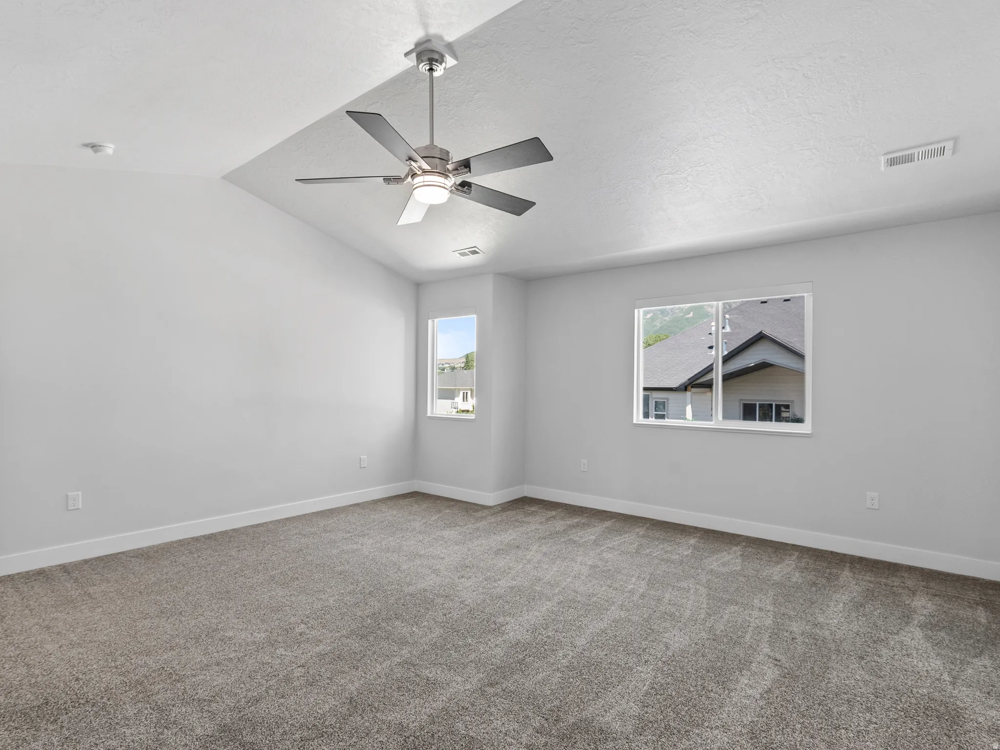Spacious room with vaulted ceiling and a contemporary ceiling fan