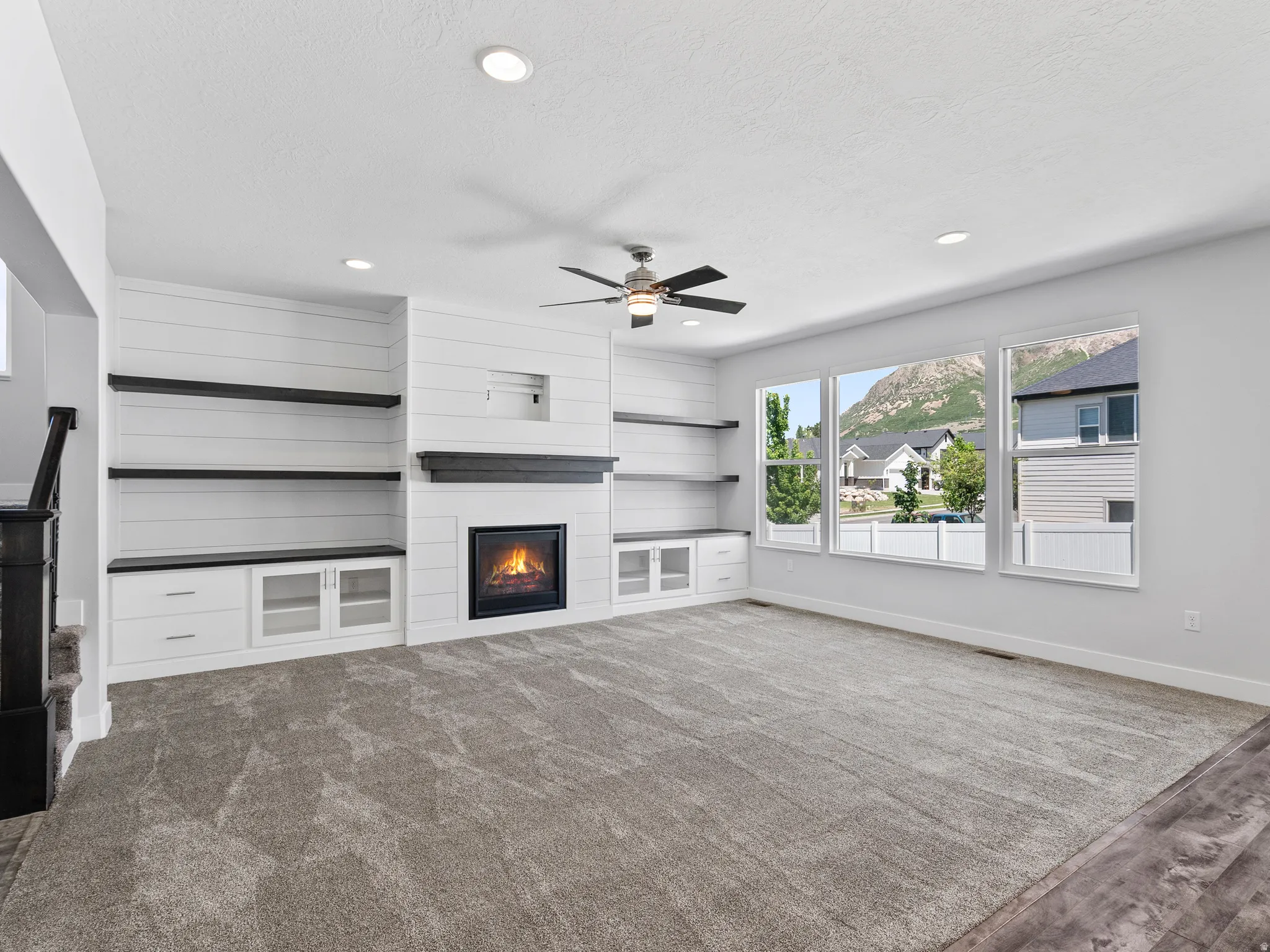 Living area featuring a modern fireplace with a dark wood mantel, flanked by built-in shelving and cabinetry