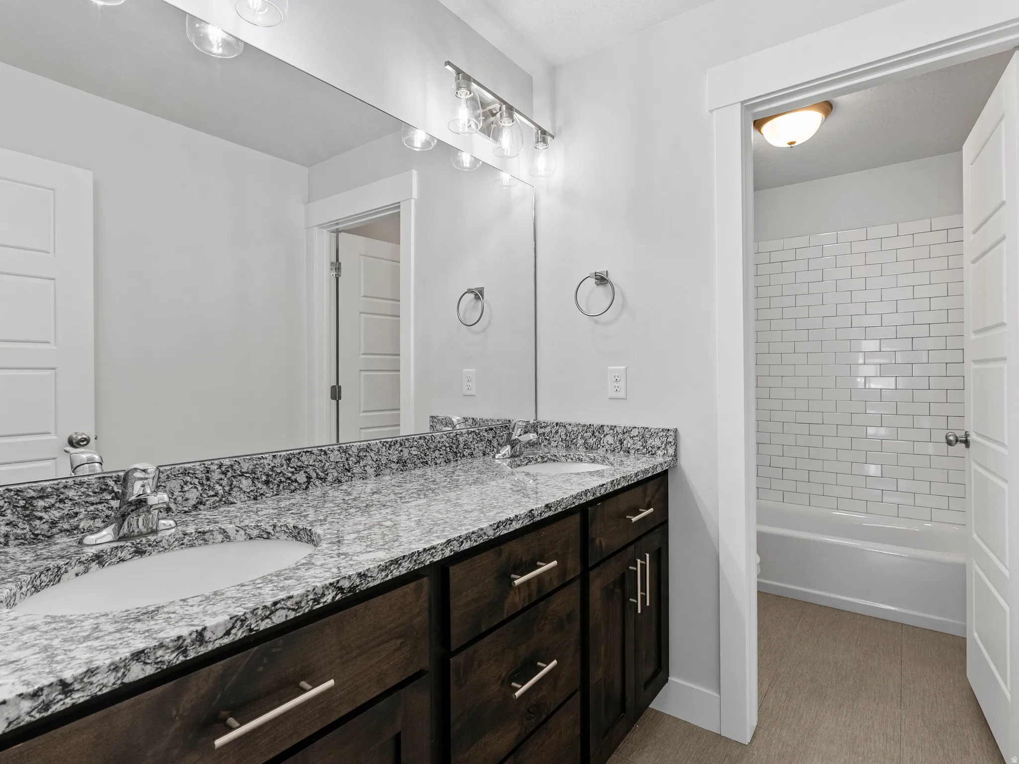 Double vanity featuring a light-toned countertop with integrated sinks and dark-stained wood cabinetry
