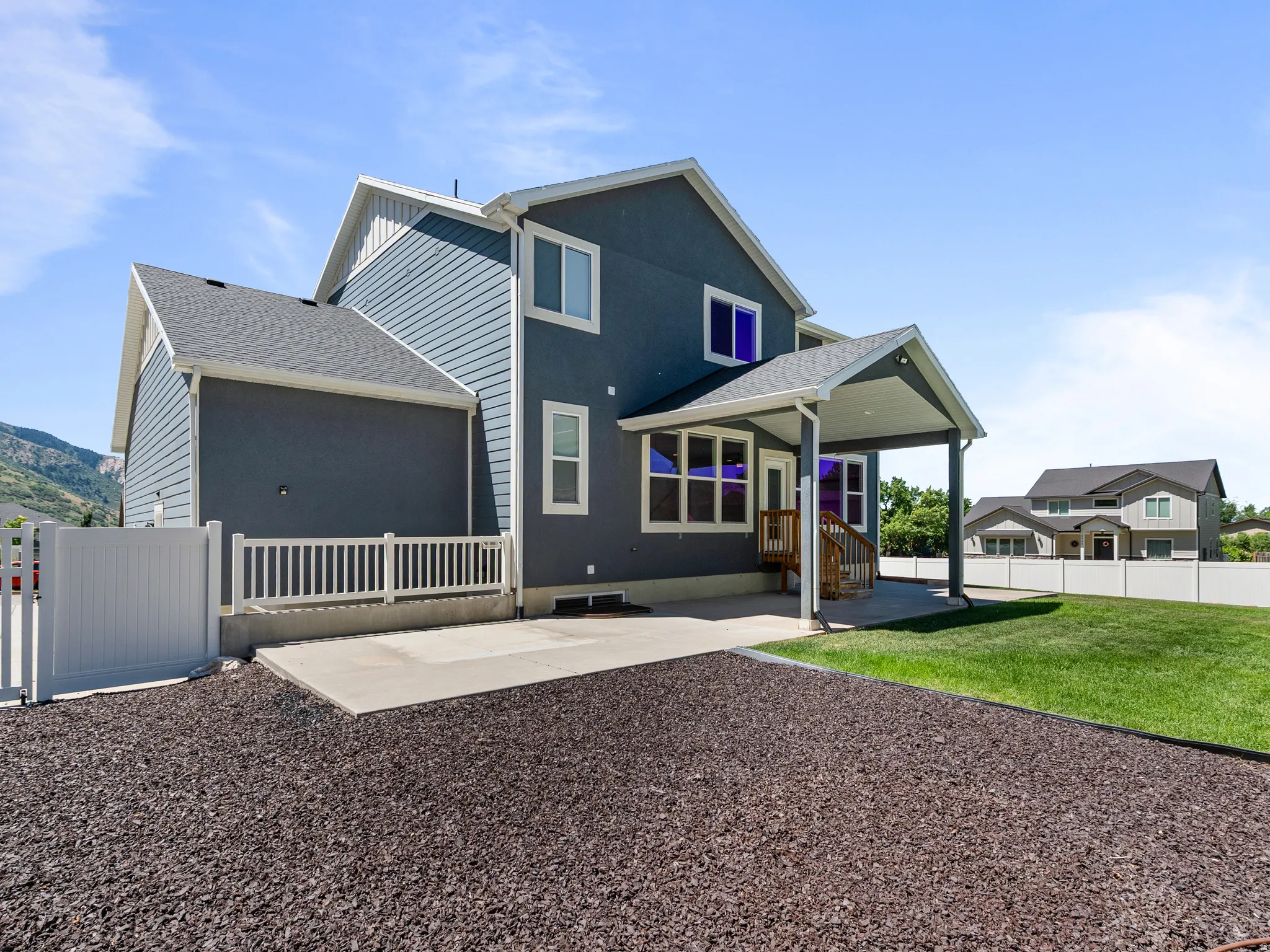 Rear exterior featuring a covered patio, concrete slab, and a wood-decked stairway