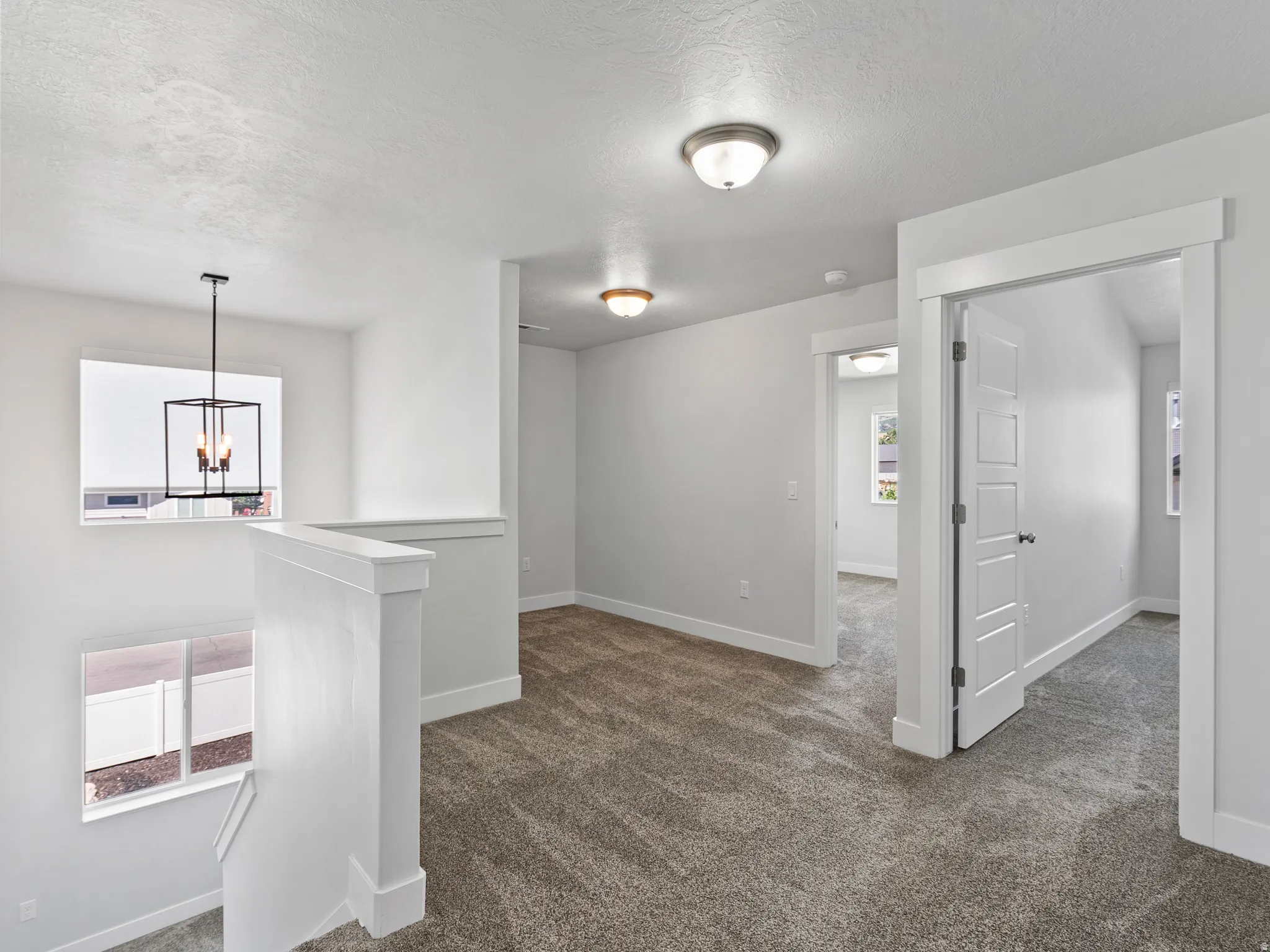 Carpeted loft area featuring white walls, white trim, and white paneled doors