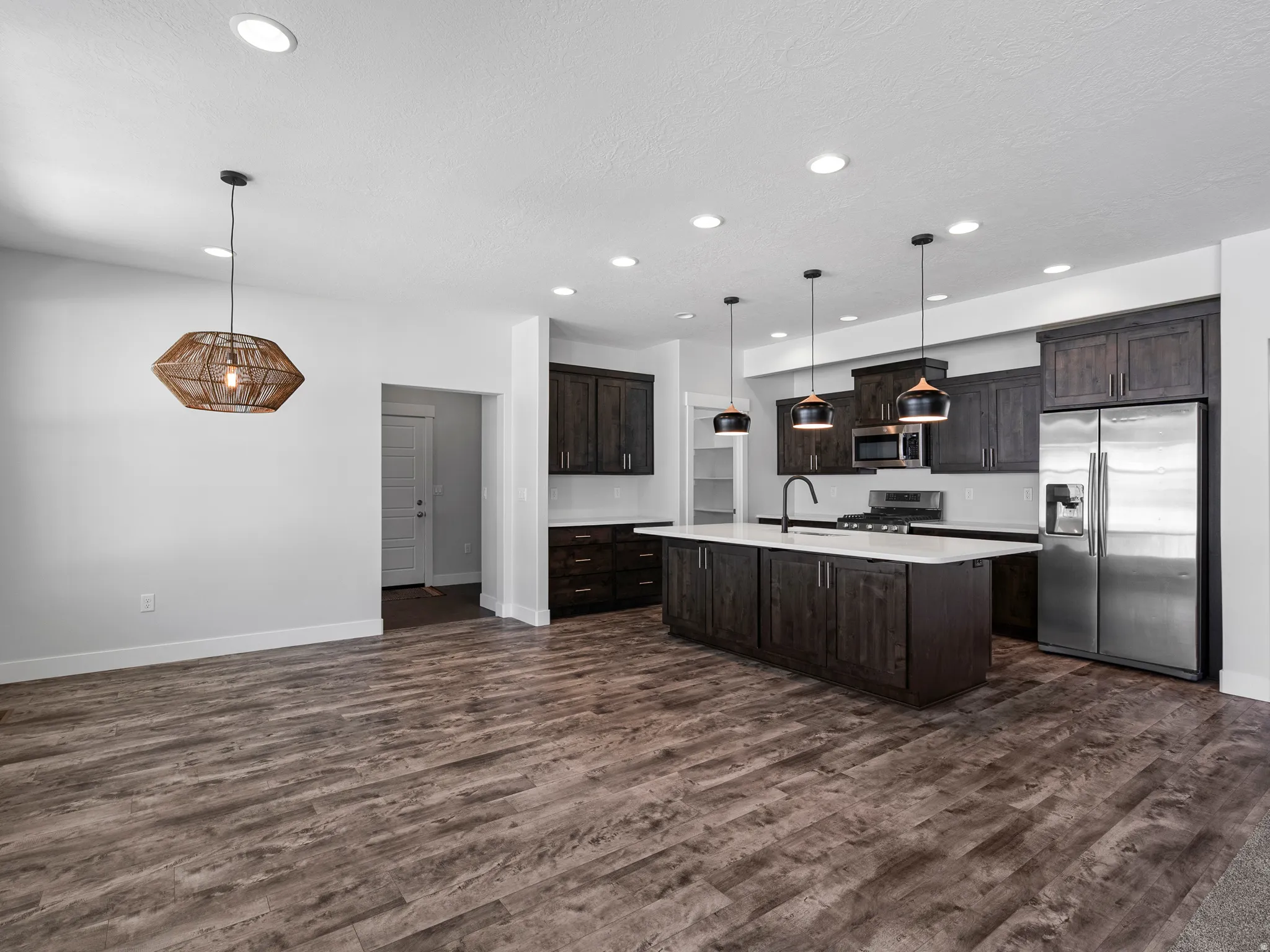 Modern kitchen featuring dark wood cabinetry, white countertops, and stainless steel appliances