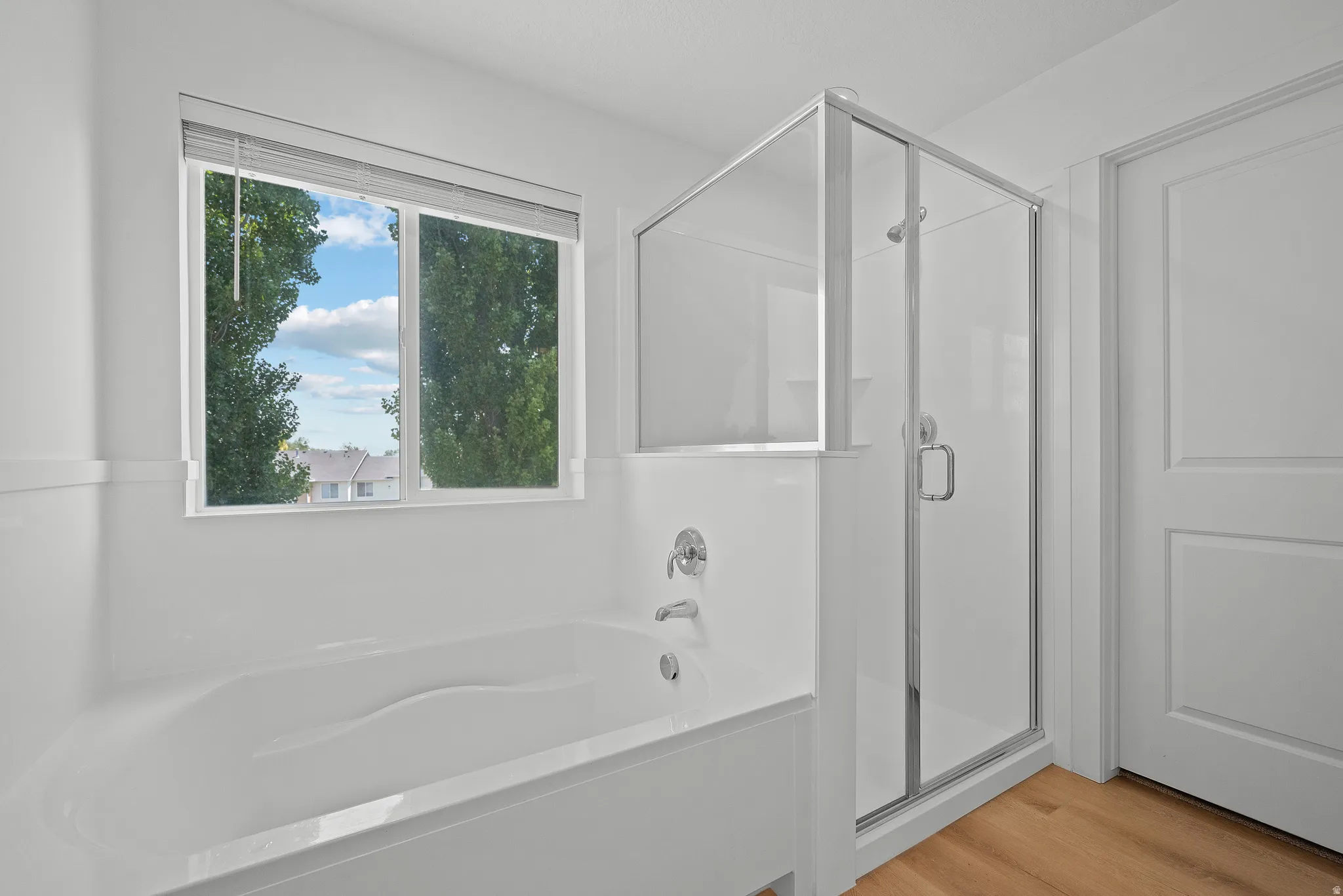 White soaking tub with chrome fixtures and an adjacent glass-enclosed shower