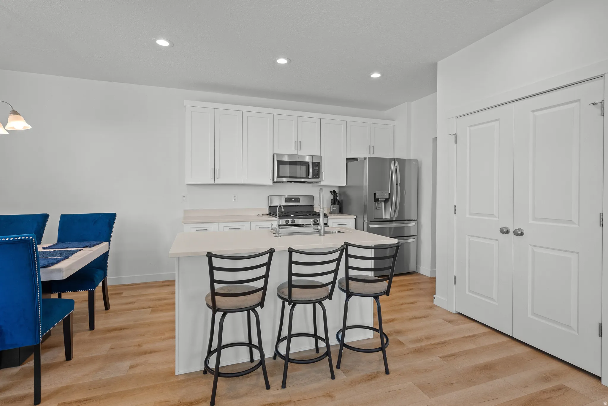 Modern kitchen featuring white shaker cabinetry, stainless steel appliances, a center island with bar seating, and light wood-finish flooring