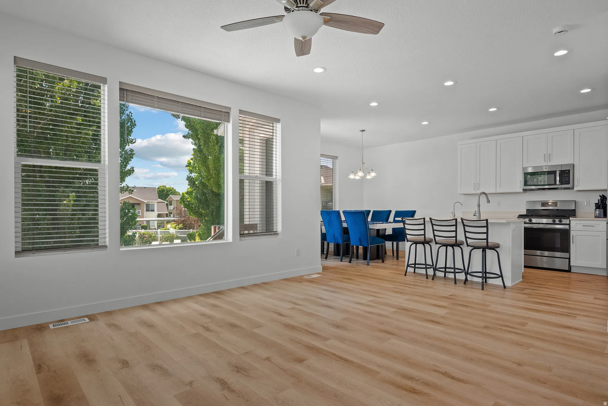 Open-concept living space with wood-finish flooring, white walls, and recessed lighting