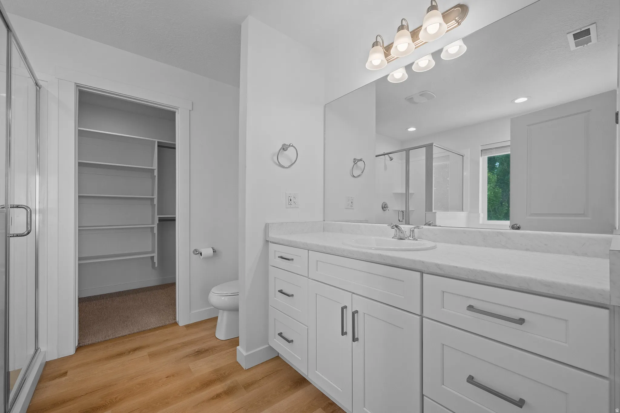 Contemporary bathroom featuring a spacious vanity with white cabinetry, a single undermount sink, and a large mirror with overhead lighting